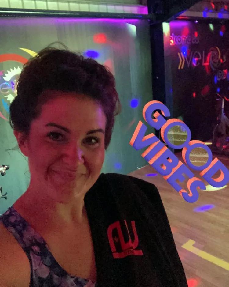 Fenn smiling in the Velocity Fitness studio under colourful disco lights